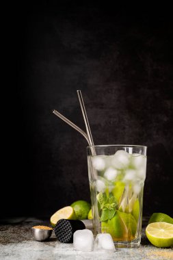 fresh summer caipirinha cocktail on concrete background with green fruit lime on table