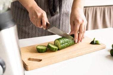 Healthy eating, dieting concept. High angle view of female hands cutting cucumber in the kitchen