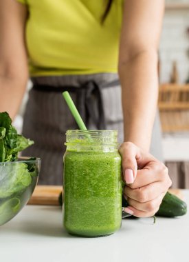 Healthy eating, dieting concept. Close up of a young woman holding a jar of green smoothie