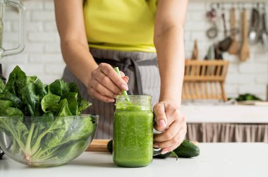 Healthy eating, dieting concept. Close up of a young woman holding a jar of green smoothie