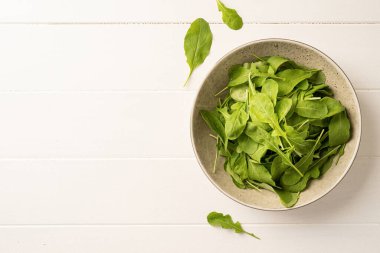 Healthy eating and dieting. Fresh arugula leaves in white bowl on wooden background top view, flat lay