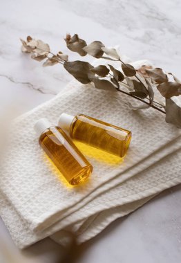 Natural cosmetics. Essential oil bottle mockup, plastic bottle with cosmetic product on white bath towels and eucalyptus leaves