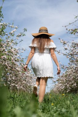 Spring concept. Nature.Young caucasian woman enjoying the flowering of an apple trees, walking in spring apple gardens