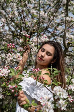Spring concept. Nature.Young caucasian woman enjoying the flowering of an apple trees, walking in spring apple gardens