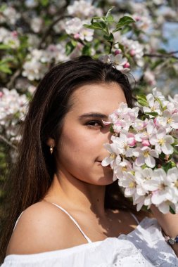 Spring concept. Nature.Young caucasian woman enjoying the flowering of an apple trees, walking in spring apple gardens