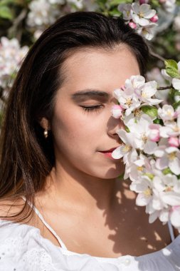 Spring concept. Nature.Young caucasian woman enjoying the flowering of an apple trees, walking in spring apple gardens
