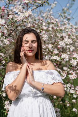 Spring concept. Nature.Young caucasian woman enjoying the flowering of an apple trees, walking in spring apple gardens. Shadow overlay on face
