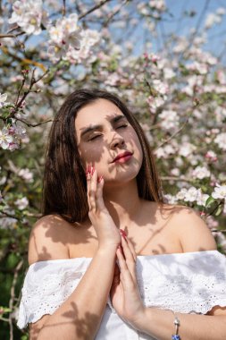 Spring concept. Nature.Young caucasian woman enjoying the flowering of an apple trees, walking in spring apple gardens. Shadow overlay on face