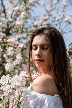 Spring concept. Nature.Young caucasian woman enjoying the flowering of an apple trees, walking in spring apple gardens