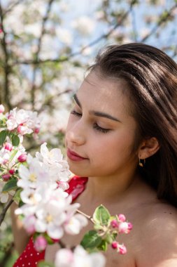 Spring concept. Nature.Young caucasian woman enjoying the flowering of an apple trees, walking in spring apple gardens