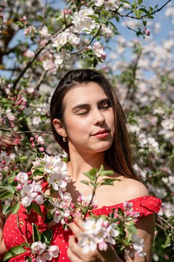 Spring concept. Nature.Young caucasian woman enjoying the flowering of an apple trees, walking in spring apple gardens