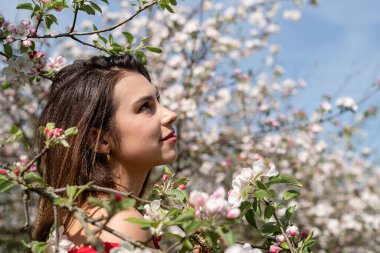 Spring concept. Nature.Young caucasian woman enjoying the flowering of an apple trees, walking in spring apple gardens