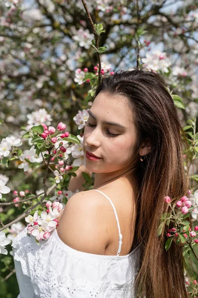 Spring concept. Nature.Young caucasian woman enjoying the flowering of an apple trees, walking in spring apple gardens