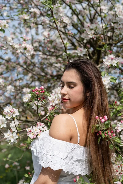 Spring concept. Nature.Young caucasian woman enjoying the flowering of an apple trees, walking in spring apple gardens