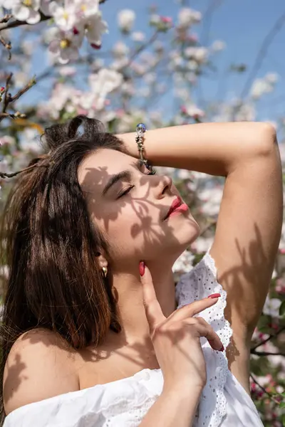 Spring concept. Nature.Young caucasian woman enjoying the flowering of an apple trees, walking in spring apple gardens