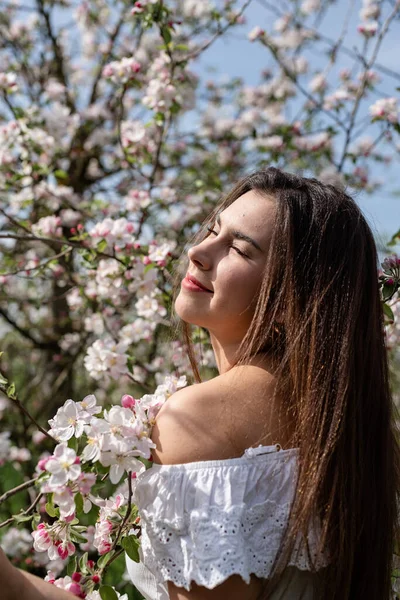 Spring concept. Nature.Young caucasian woman enjoying the flowering of an apple trees, walking in spring apple gardens