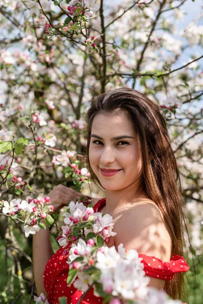 Spring concept. Nature.Young caucasian woman enjoying the flowering of an apple trees, walking in spring apple gardens