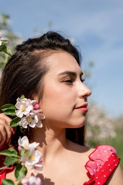 Spring concept. Nature.Young caucasian woman in red dress and summer hat enjoying the flowering of an apple trees, walking in spring apple gardens