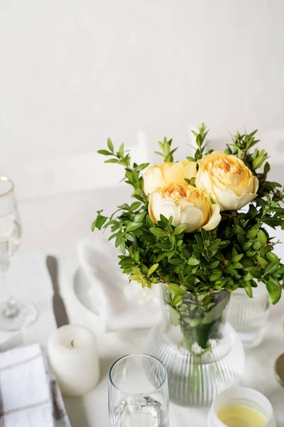 Wedding table set up in taditional style with roses grass and greenery. Close up of beige roses bouquet