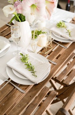 The wedding table setting and decor on wooden table in rustic style. Wedding table scapes. Table set up with boxwood and amaryllis flowers