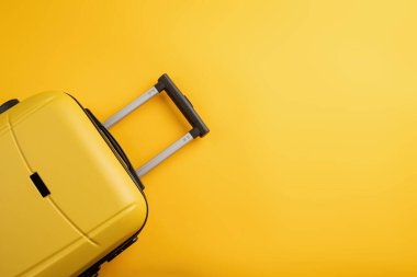 travel plan, trip and vacation, minimal. Top view yellow travel bag or suitcase on solid yellow background with copy space