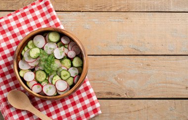 Bowl of healthy vegetarian salad with radish cucumber and fennel. top view on wooden background with copy space, summer food