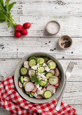 Bowl of healthy vegetarian salad with radish cucumber and fennel. top view on wooden background with copy space, summer food