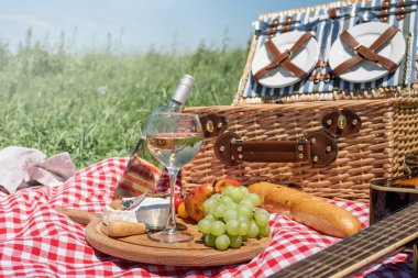 Closeup of picnic basket with drinks and food on the grass. Nice picnic on sunny summer day, fun and leisure