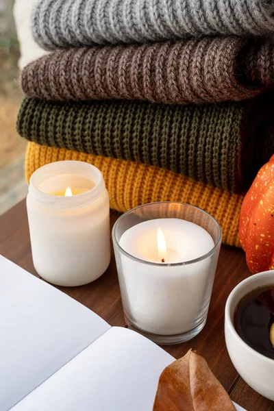 Hello fall. Cozy warm image. High angle view autumn composition with sweaters and candles, mockup design