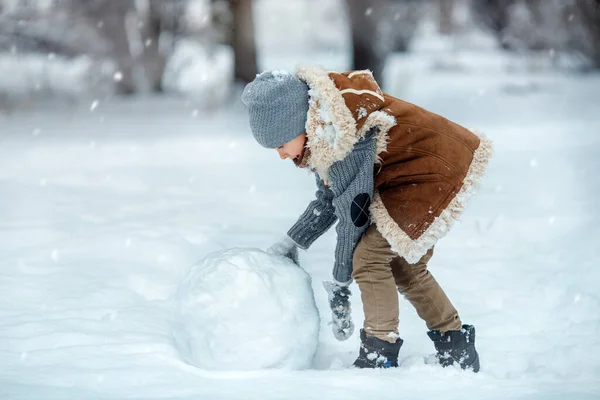 男孩在打滚雪球，以制造雪人. — 图库照片