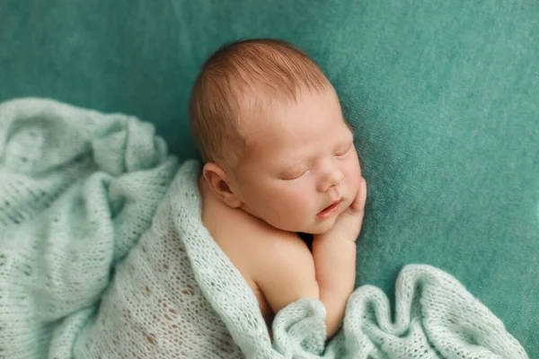 Alvó újszülött, zöld háttérrel, takaróval borítva. — Stock Fotó