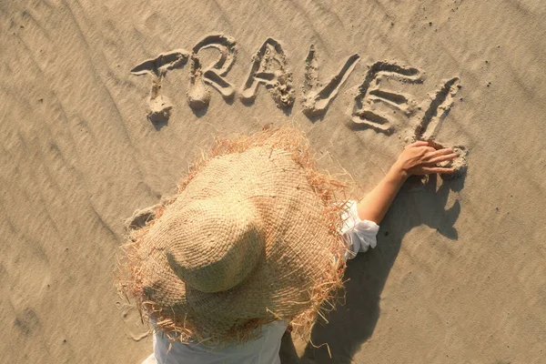 Jonge vrouw schrijven op zand "reizen" — Stockfoto