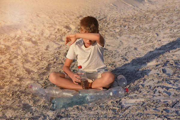 Trauriger Junge trinkt Wasser auf Rissboden — Stockfoto