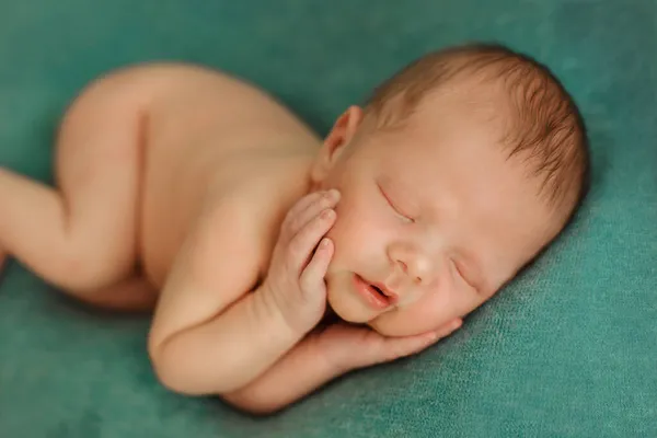 Yeşil arka planda uyuyan yeni doğmuş bebek