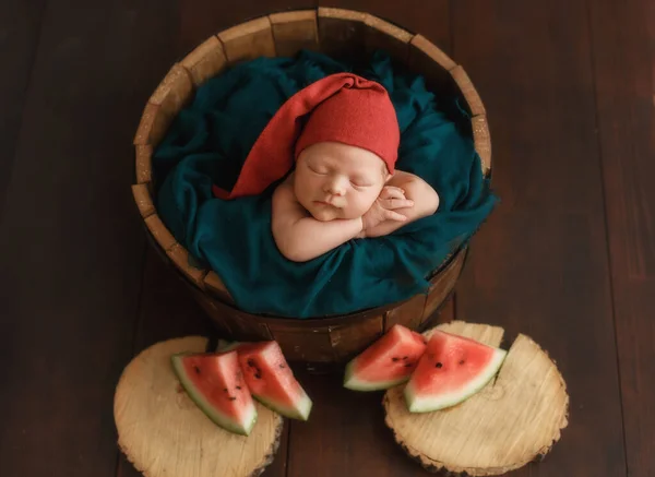 Bebê recém-nascido em um balde com melancia. — Fotografia de Stock