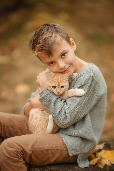 Kind met gember kat in een herfstpark — Stockfoto