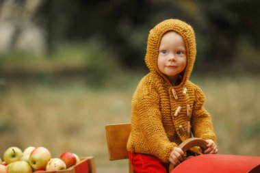 Kızıl kazaklı çocuk küçük, tahta bir traktörde.