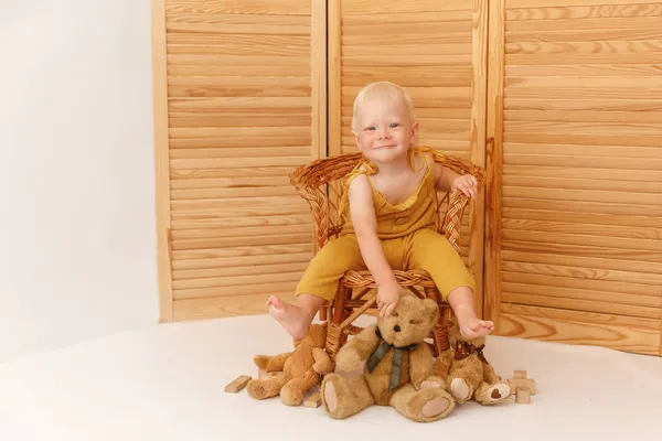 Jongen zit op een fauteuil en houdt een teddybeer vast — Stockfoto