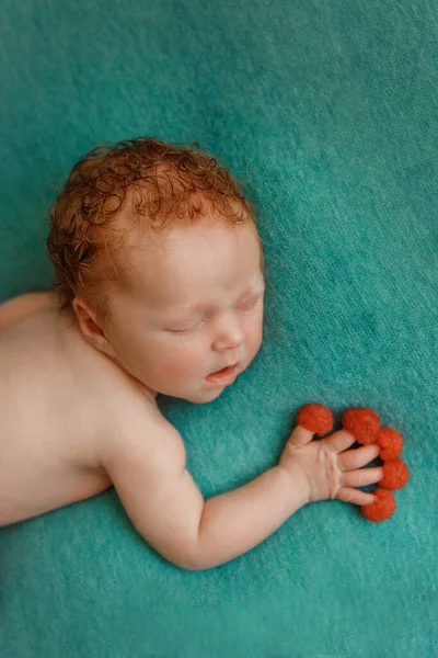 Bebê recém-nascido adormecido em um fundo verde segurando framboesas, — Fotografia de Stock