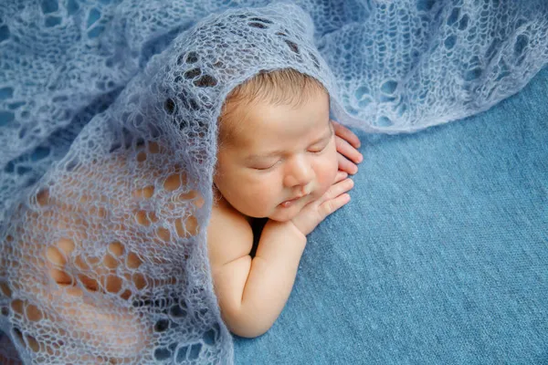 Bebé recién nacido dormido sobre un fondo azul cubierto por una manta. — Foto de Stock