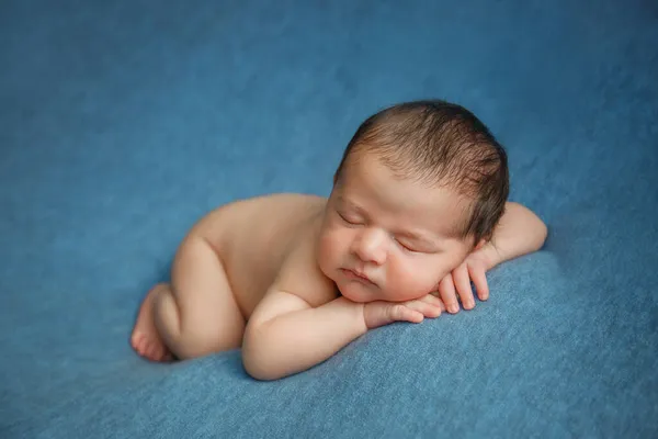 Alvó újszülött, kék háttérrel, takaróval borítva. — Stock Fotó