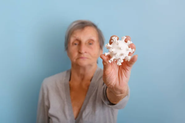 Egy idős nőnél van egy coronovírus modell. — Stock Fotó