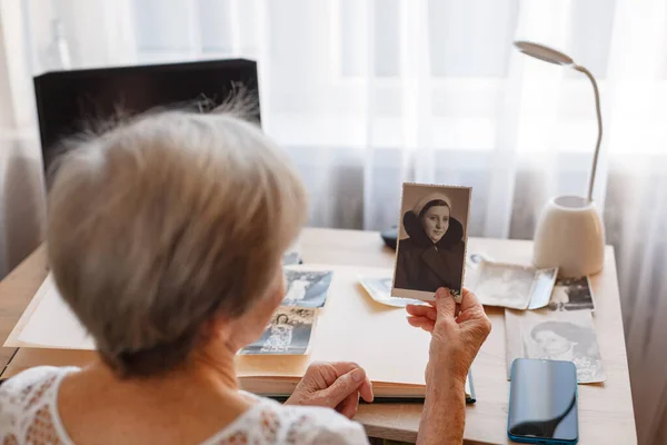 Yaşlı kadın kendi eski fotoğraflarına bakıyor..