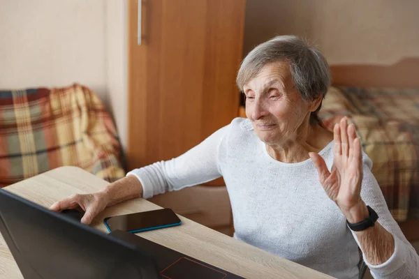 80er-Jahre-Seniorin winkt mit Laptop. — Stockfoto
