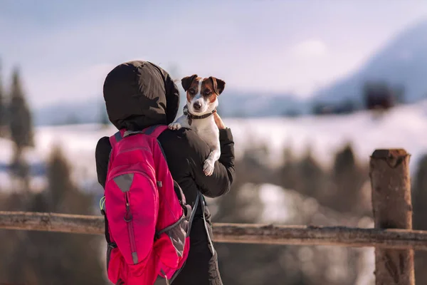穿着夹克背着背包牵着狗在山里的女人 — 图库照片
