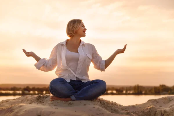 Lotuslu kadın gün batımında sahilde poz verir. 