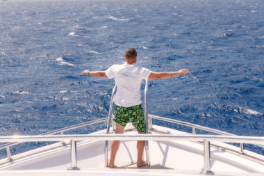 Lüks bir yatta yelken açan adam. Gemideki kişinin arka görüntüsü. Erkekler tatilde vakit geçirir.. 