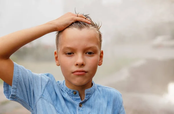  Yağmurdan sonra dışarıda şık saç stili olan gülümseyen çocuk. Kameraya bakıyorum. Gençlik portresi . 