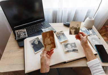Eski eller. Kıdemli kadın 1955, 1957,1967 'de çekilmiş kendi fotoğraflarını arıyor. Emekli insan ne kadar genç olduğunu hatırlarken gülümser. Seçici odak. 