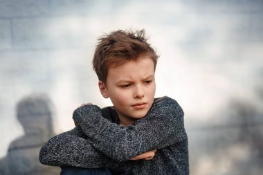 Üzgün çocuk duvarın yanında oturuyor.. 